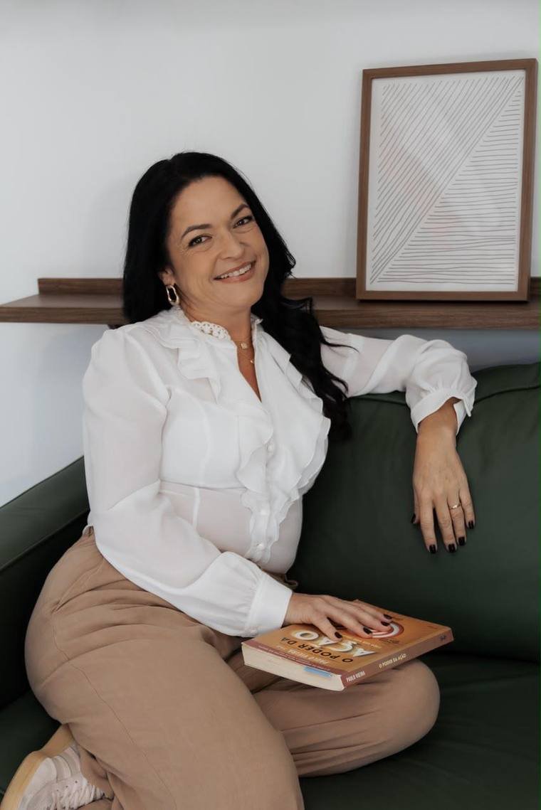 Andresa Maranha sentada no sofá segurando um livro